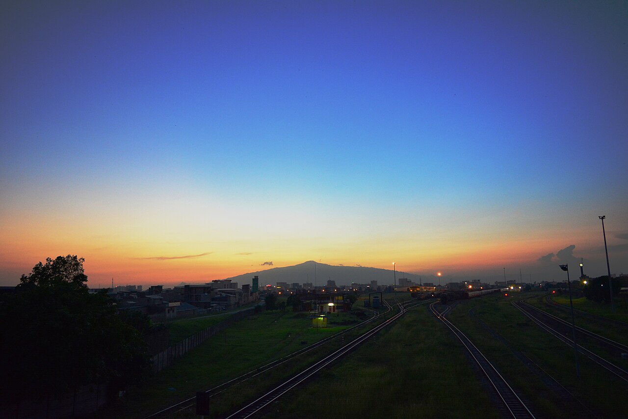 Dusk over railway tracks at Douala Bessengué station in Cameroon, with Mount Cameroon on the horizon