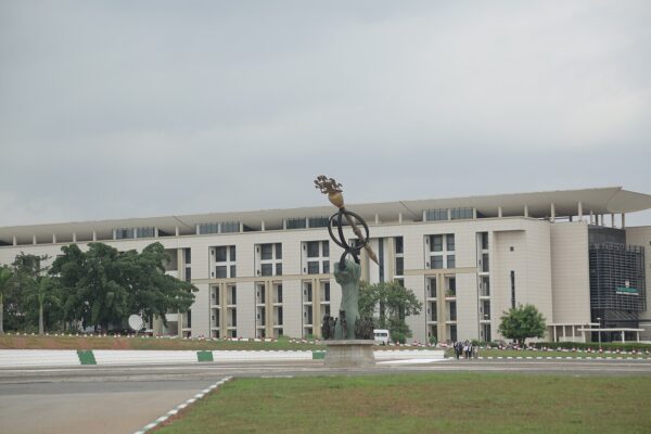 The National Assembly Complex in Abuja, Nigeria, with a sculpture of a raised hand holding a ceremonial mace in front of the building