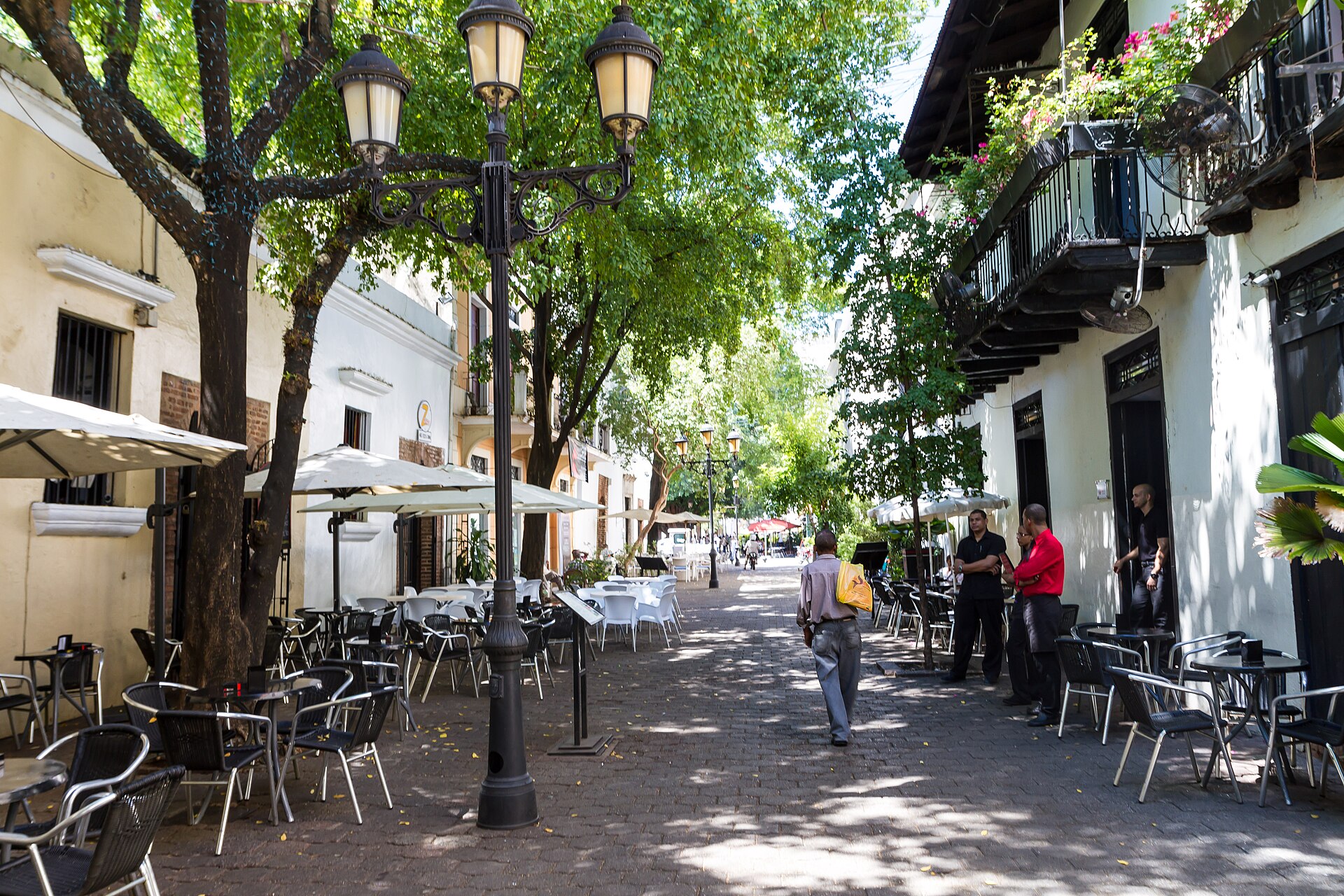 A pedestrian street lined with cafe tables and street lamps in the Zona Colonial of Santo Domingo