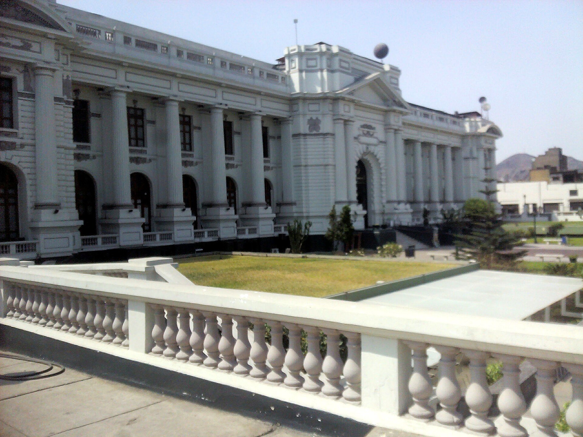 Side view of the white Legislative Palace building in central Lima behind a stone balustrade