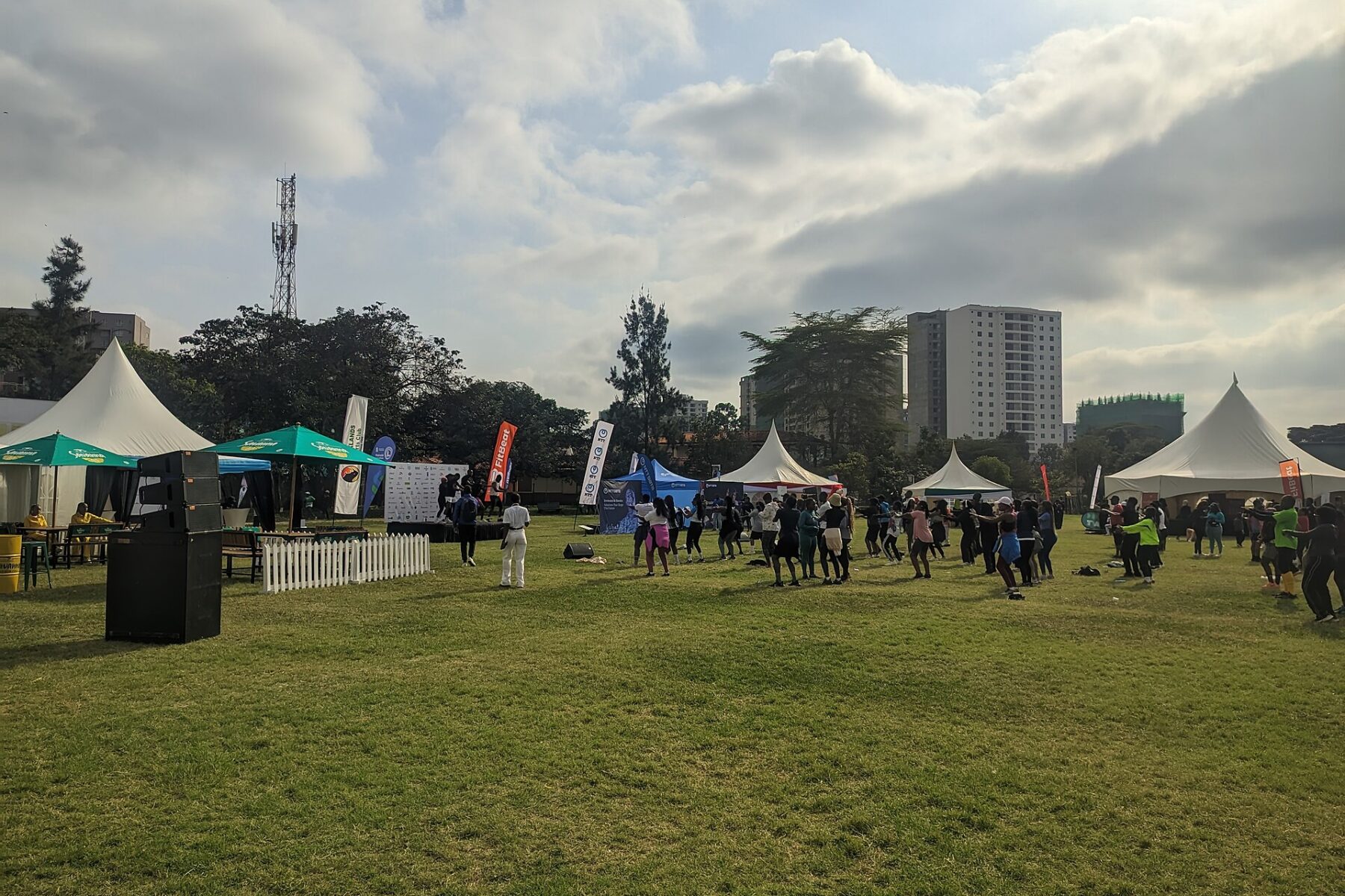 Runners in a group workout on the lawn at Parklands Sports Club in Nairobi during a Standard Chartered Nairobi Marathon warm-up event, with tents and apartment towers behind