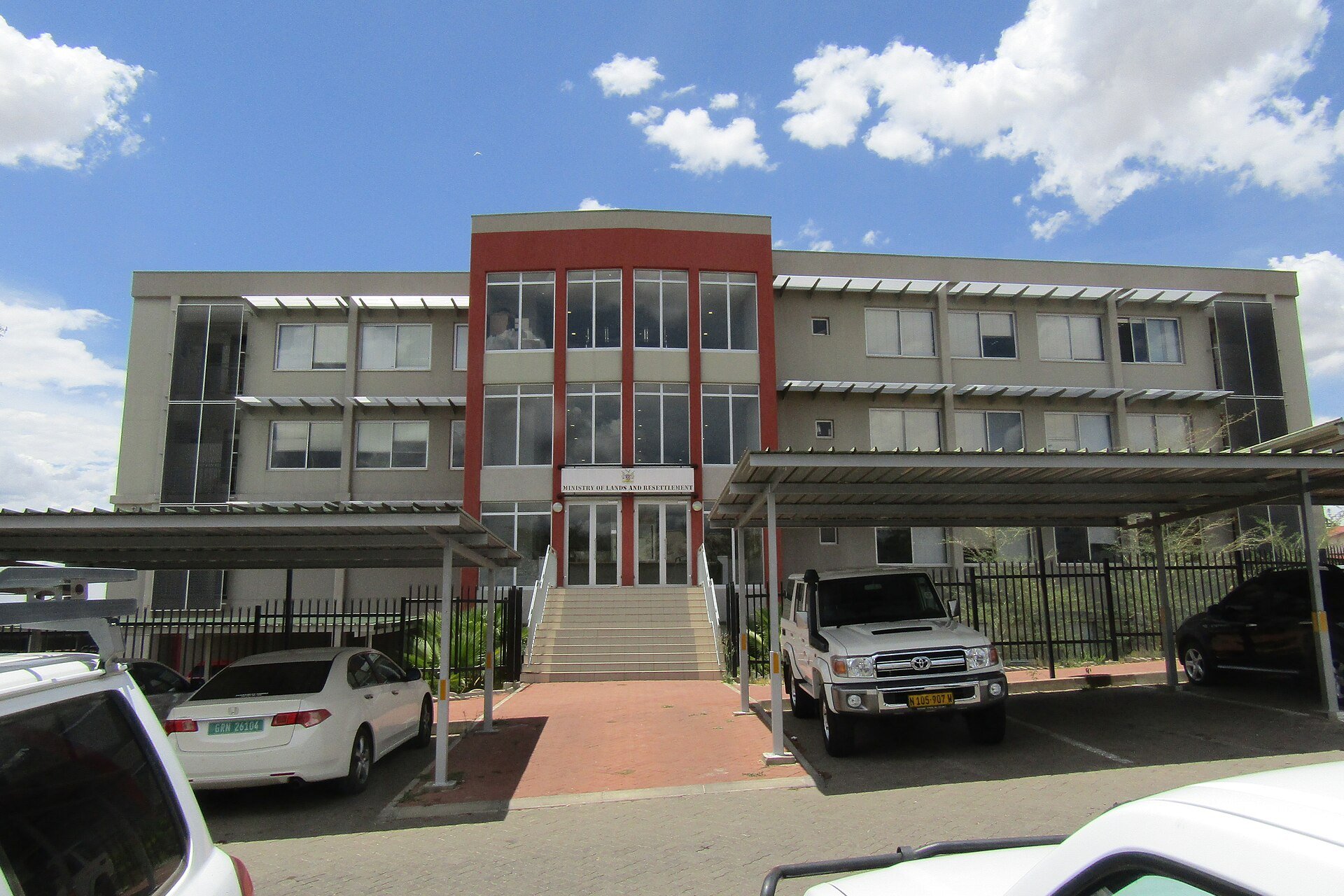 Three-storey headquarters building of Namibia's land ministry in Windhoek with a red entrance tower and a sign reading Ministry of Lands and Resettlement