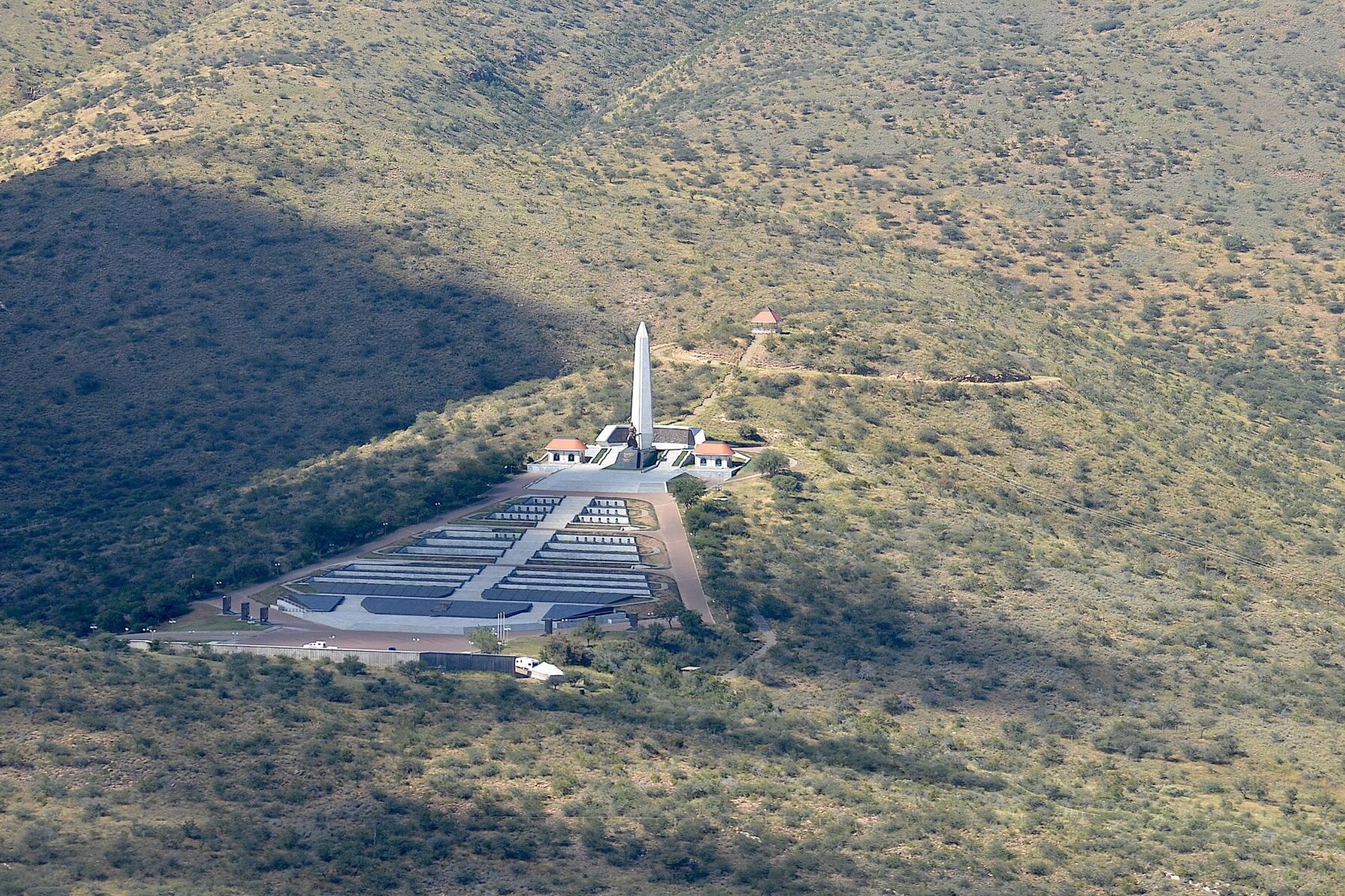 Aerial view of Heroes' Acre, the national memorial with a white obelisk and rows of graves on a hillside near Windhoek, Namibia