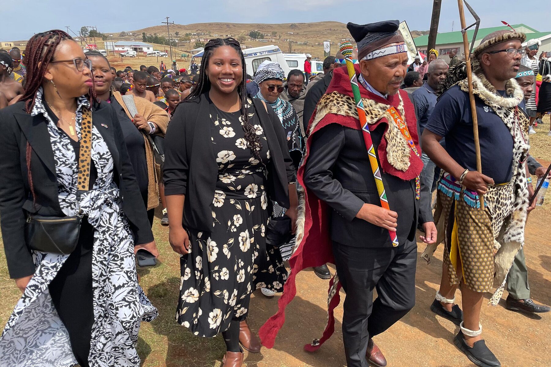Guests in traditional South African dress, including leopard-skin capes and beaded staffs, walk in a Heritage Day procession