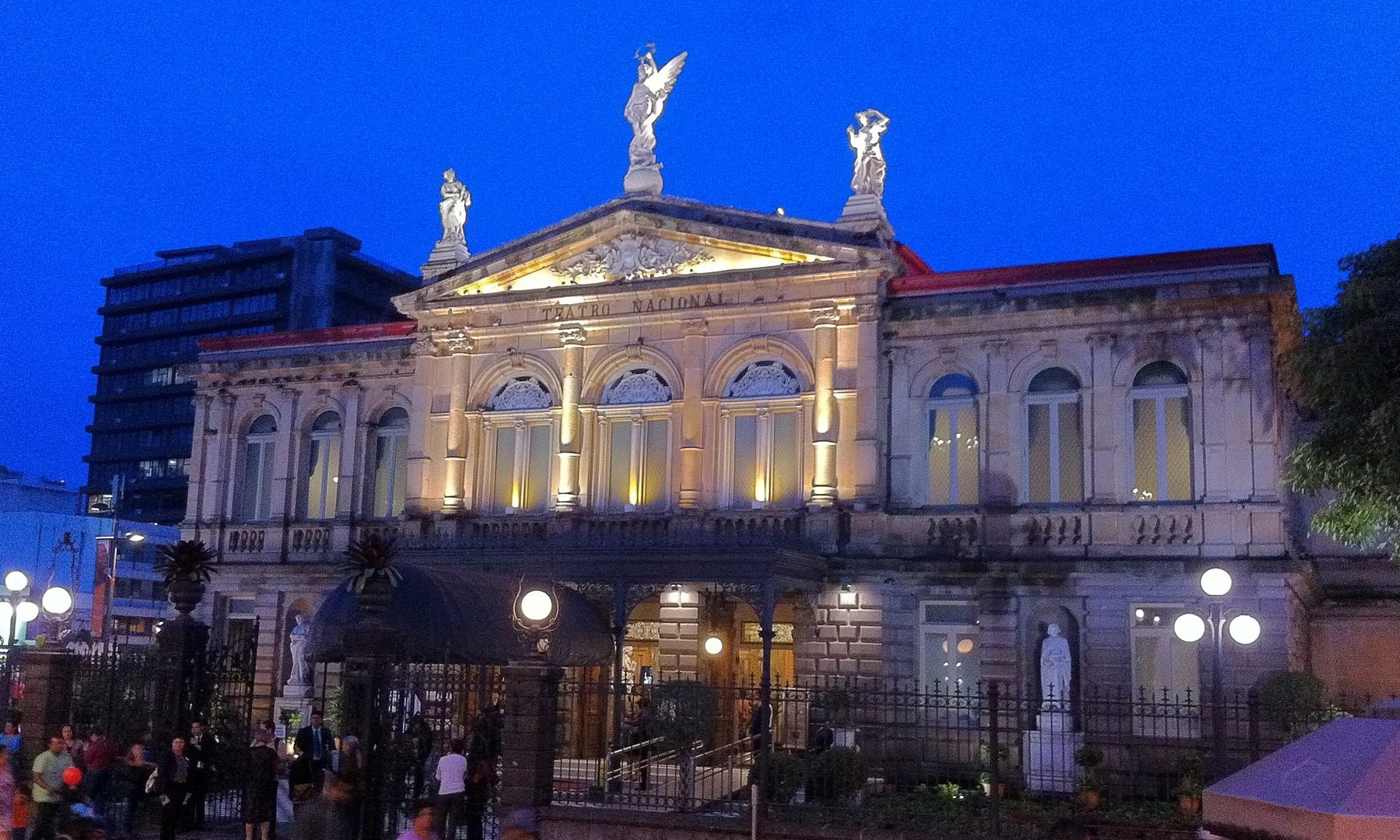 Facade of the Teatro Nacional in San Jose, Costa Rica, lit at dusk with people outside