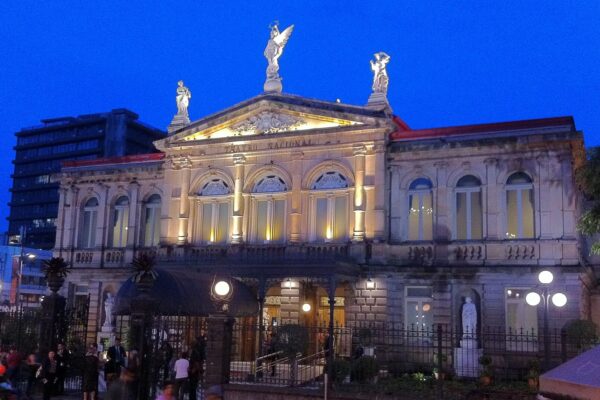 Facade of the Teatro Nacional in San Jose, Costa Rica, lit at dusk with people outside