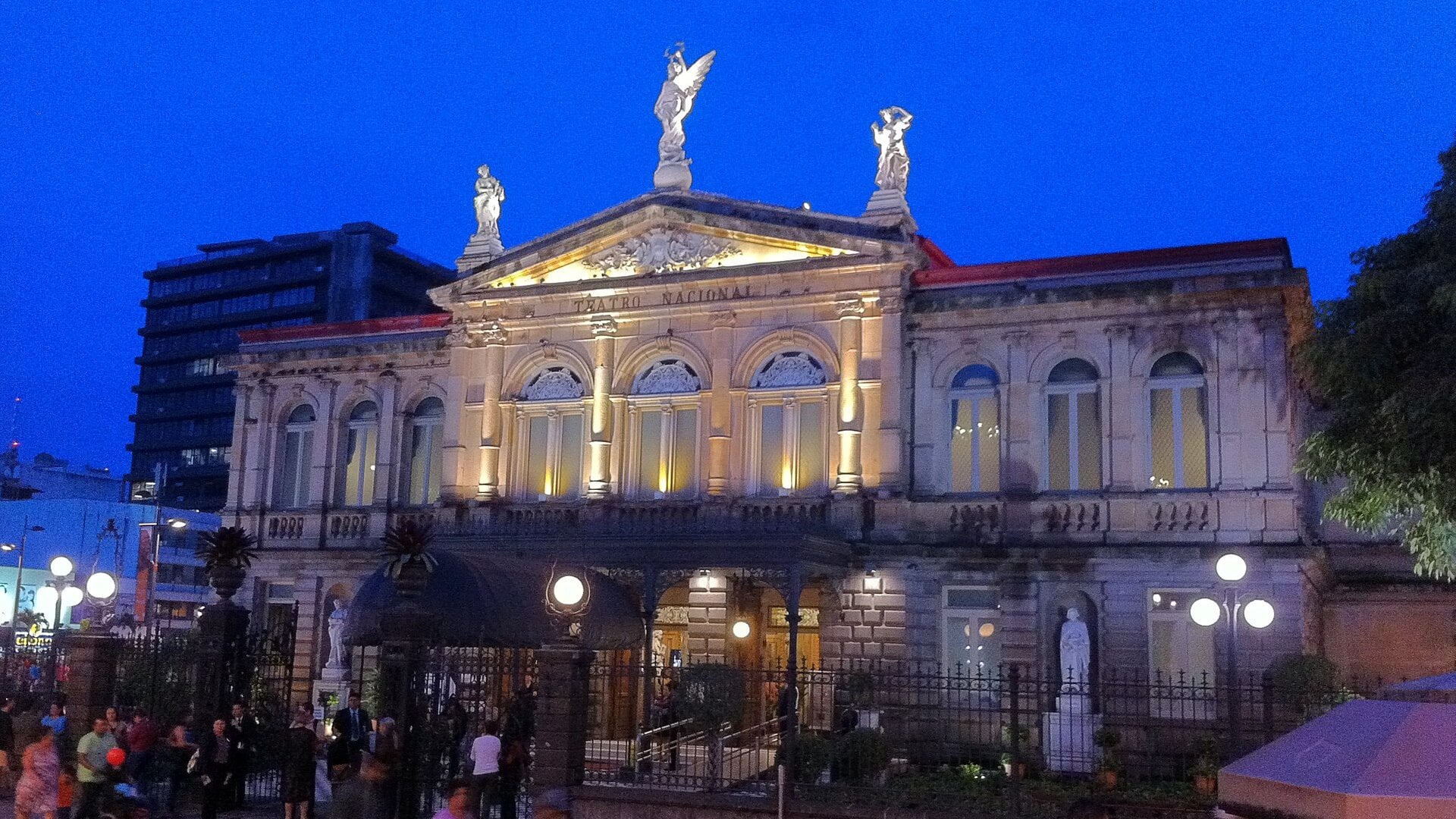 Facade of the Teatro Nacional in San Jose, Costa Rica, lit at dusk with people outside