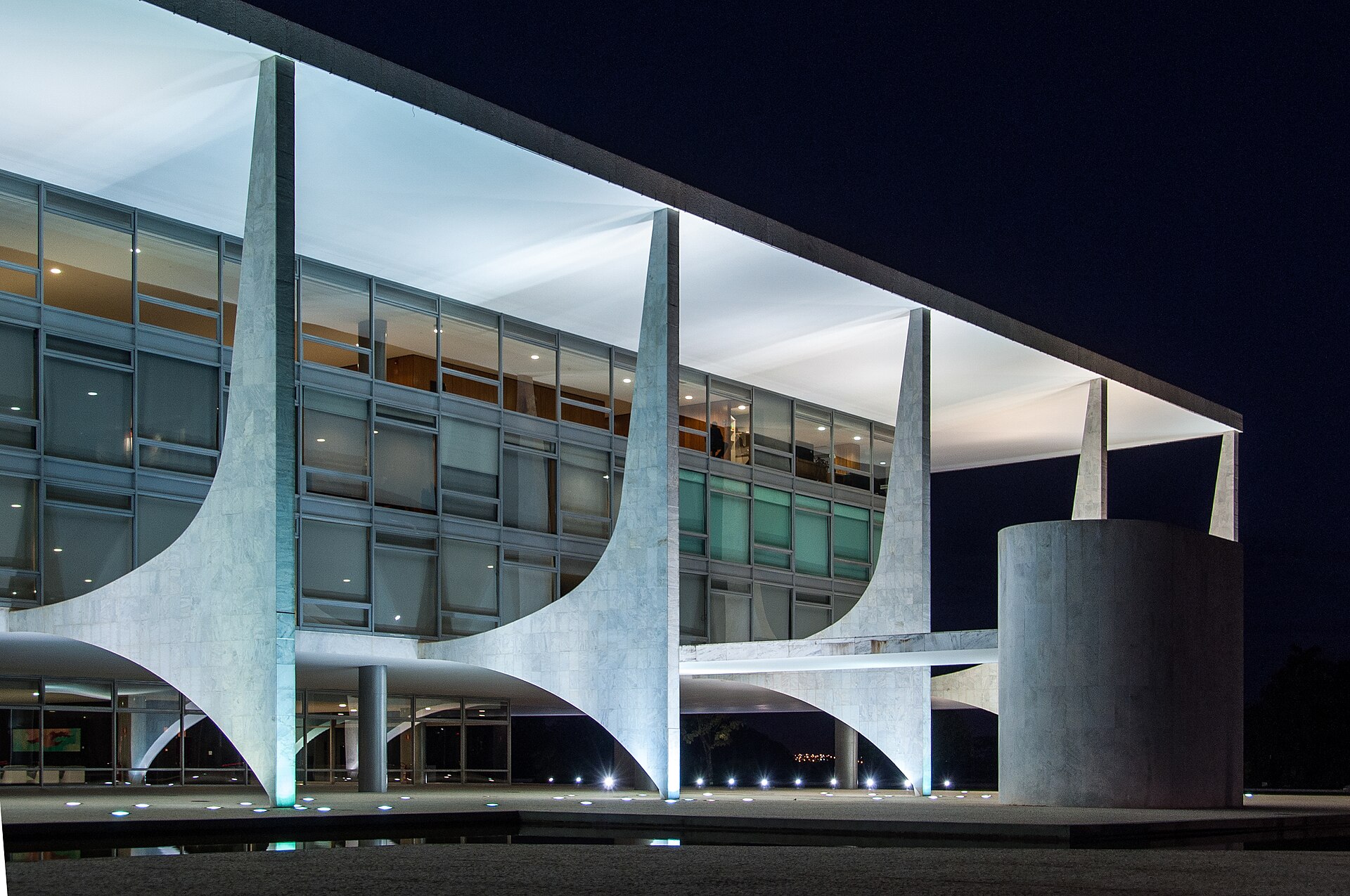 Close view of the curved concrete columns and glass front of the Palácio do Planalto in Brasília at night