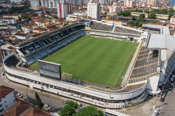 Aerial view of the Vila Belmiro football stadium in Santos, with the green pitch, curved white outer wall and surrounding houses and apartment blocks