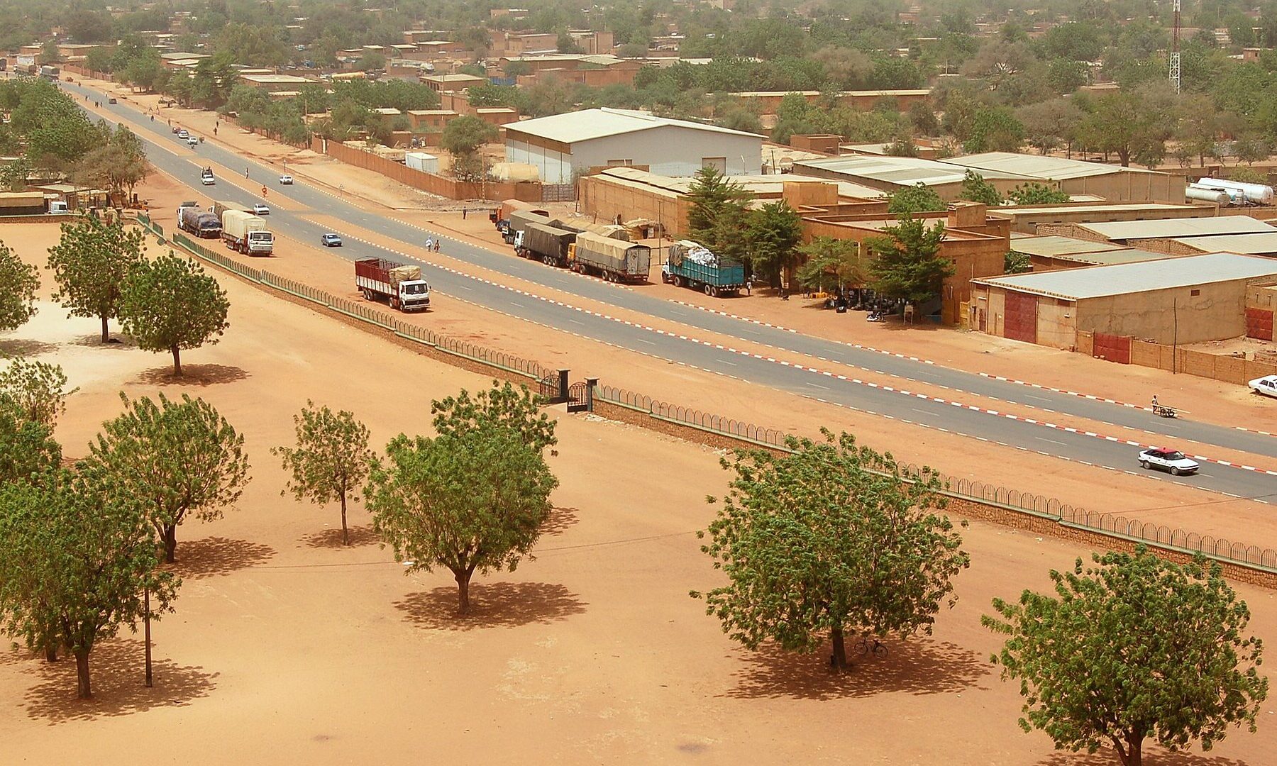 A main road in Niamey, the capital of Niger, seen from above with trucks, warehouses and trees