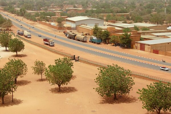 A main road in Niamey, the capital of Niger, seen from above with trucks, warehouses and trees