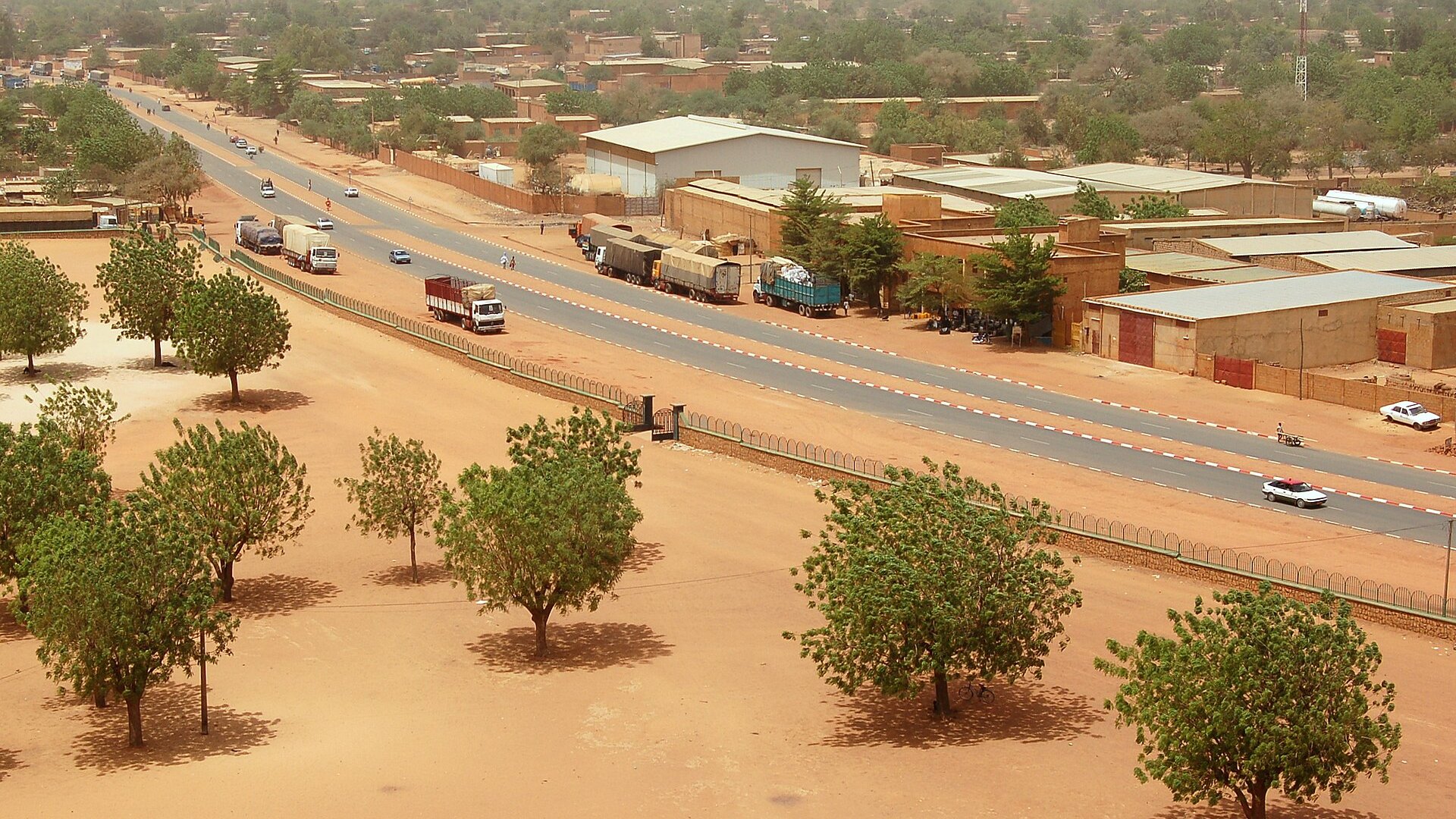 A main road in Niamey, the capital of Niger, seen from above with trucks, warehouses and trees