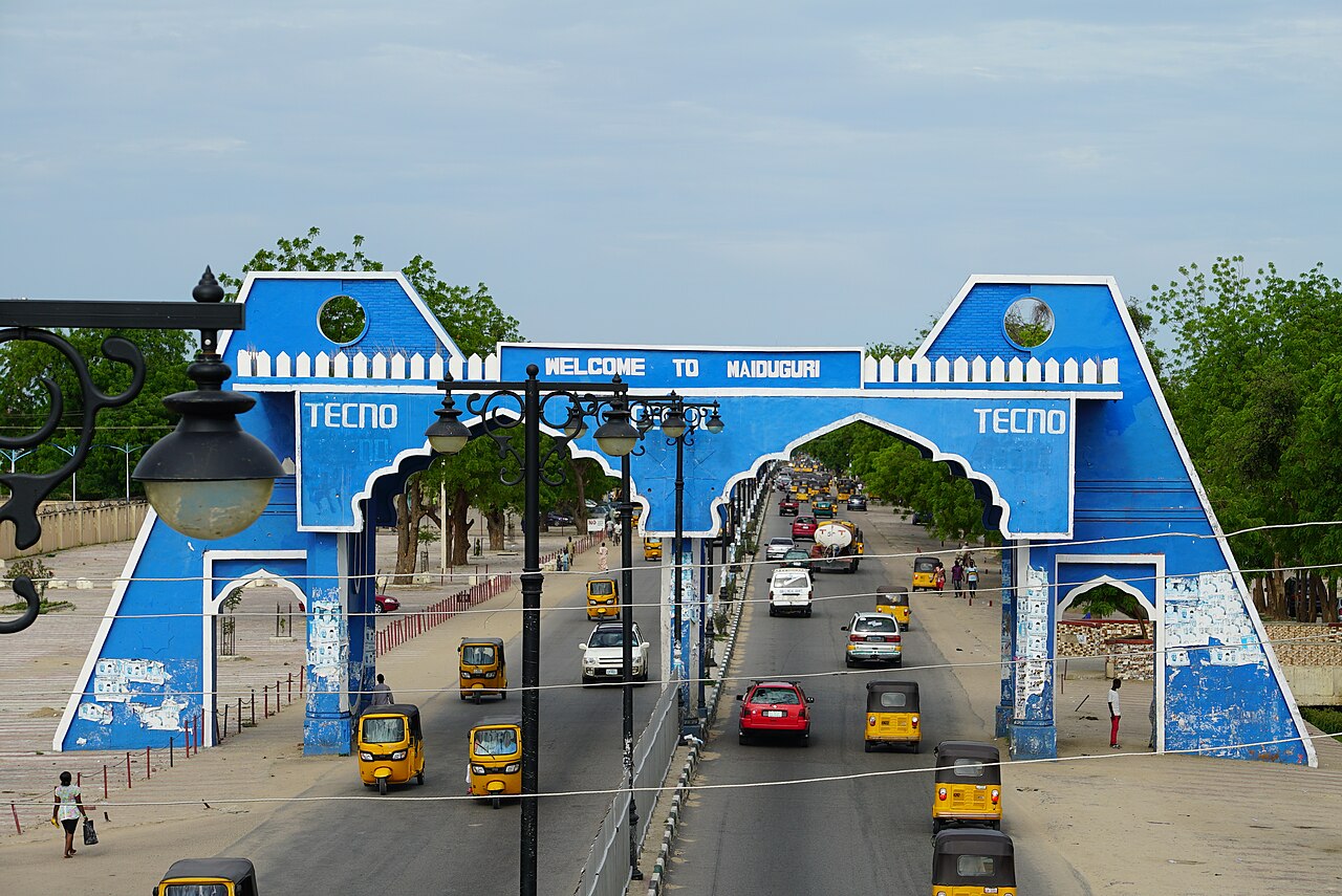 Blue welcome arch over a busy road at the entrance to Maiduguri, Nigeria.
