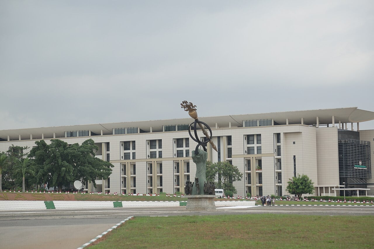 The National Assembly Complex in Abuja, Nigeria, with a sculpture of a raised hand holding a ceremonial mace in front of the building