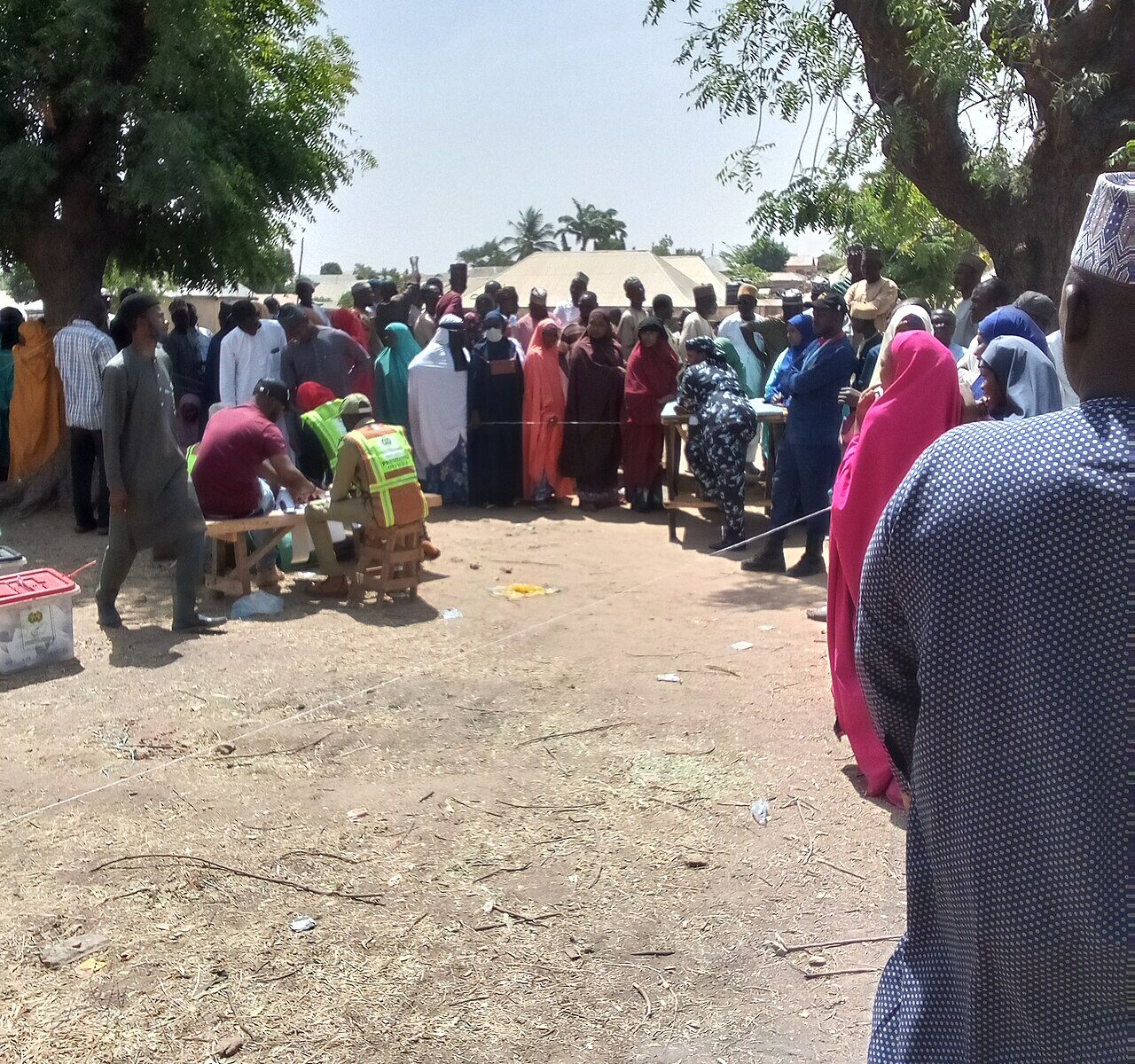 Voters and officials in bright vests gather around a table under trees at a polling unit in Pantami, Gombe, northern Nigeria