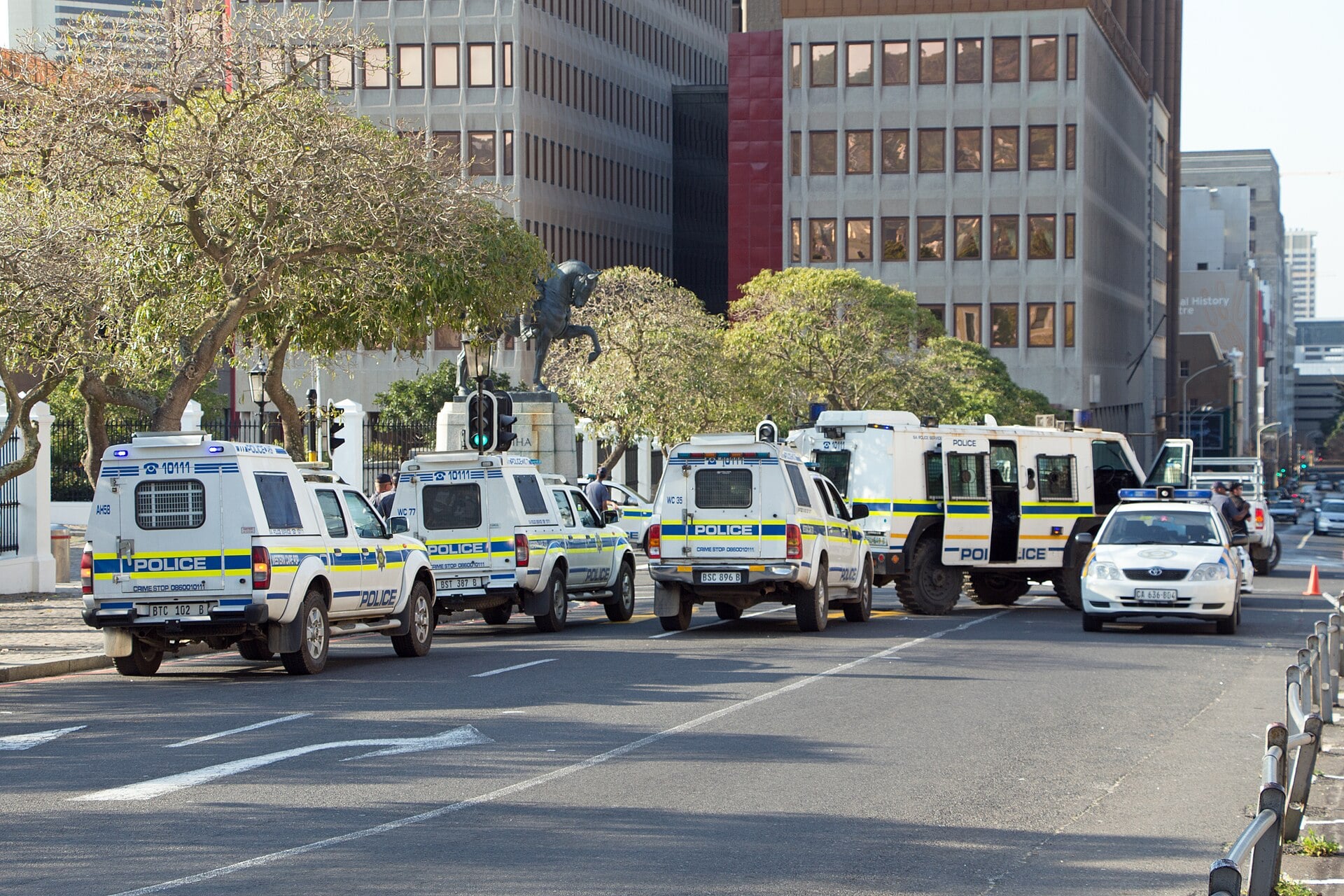 South African Police Service pickup trucks, an armoured vehicle and a police car lined up outside the Houses of Parliament in Cape Town