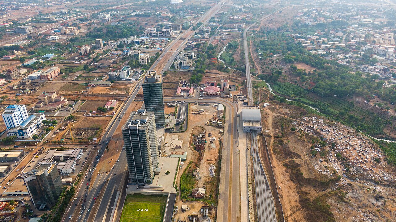 Aerial view of Abuja's Central Business District with two glass office towers, wide roads and a railway line