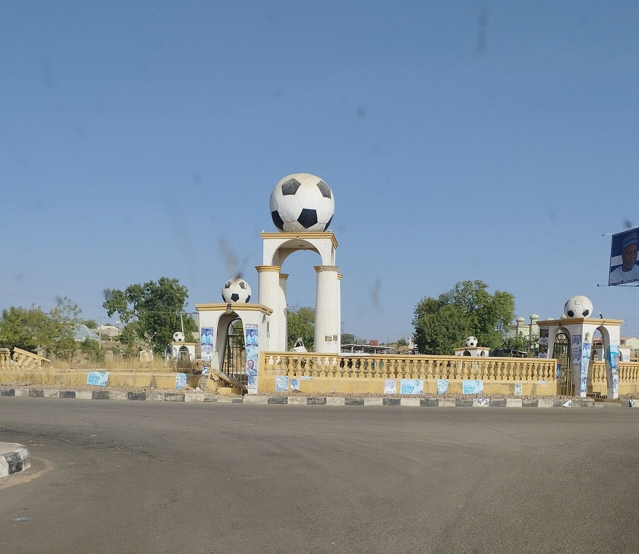 A roundabout in Gombe with a football monument and political posters on its railings