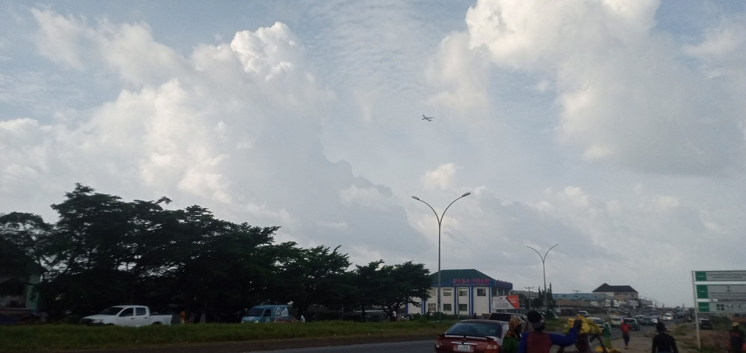 A road and roadside buildings under a cloudy sky in Abuja, Nigeria