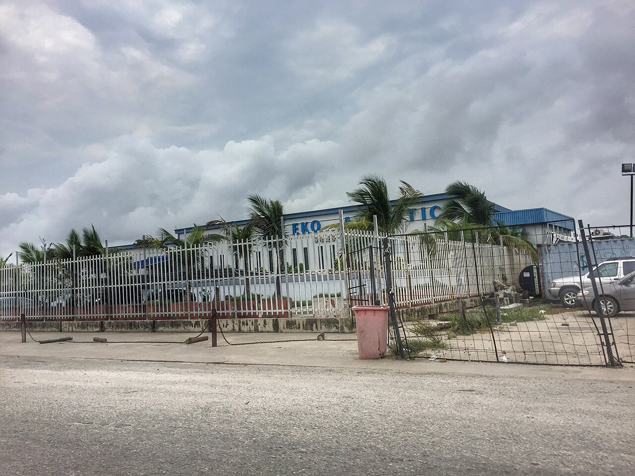 A fenced blue-roofed building with palm trees and the partly visible sign Eko Atlantic at the entrance of Eko Atlantic City in Lagos