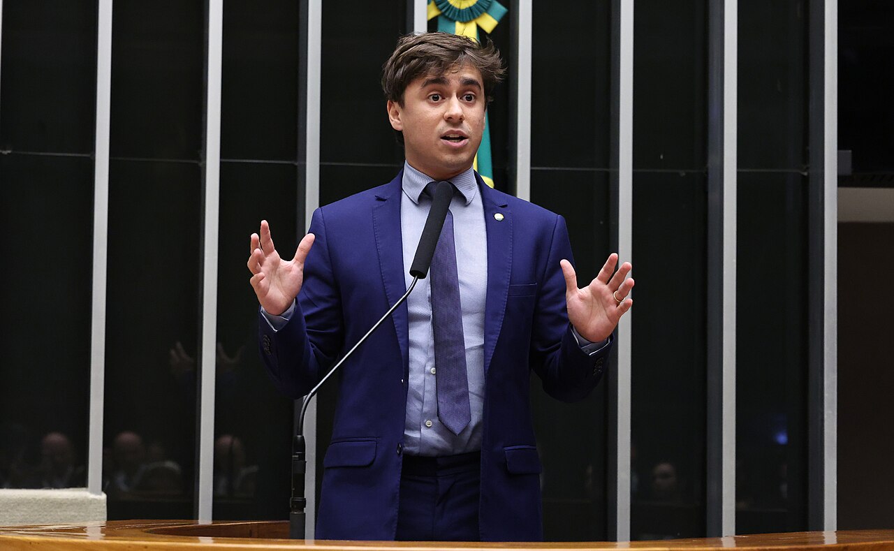 Deputy Nikolas Ferreira in a blue suit speaks at the rostrum of the Chamber of Deputies in Brasília