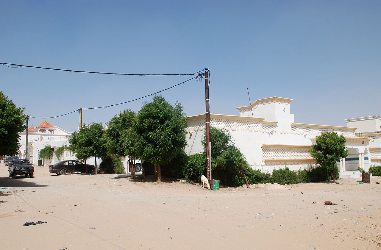 Unpaved sandy street lined with white villas and trees in a residential district of Nouakchott, Mauritania