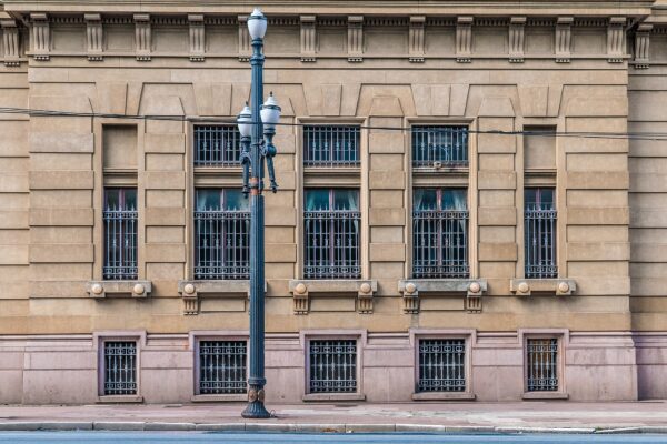 The sandstone side facade of the Palacio da Justica in Sao Paulo, with barred windows and a black iron street lamp in front