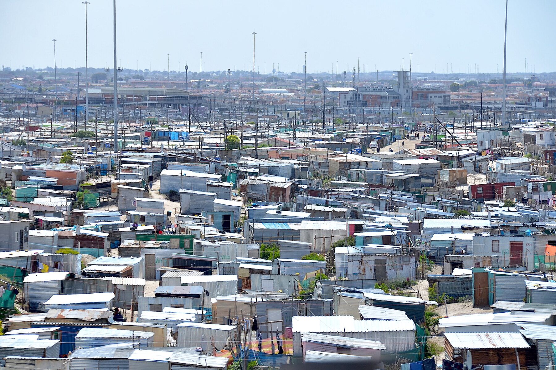 Rows of corrugated metal homes in Khayelitsha stretch to the horizon under a pale sky