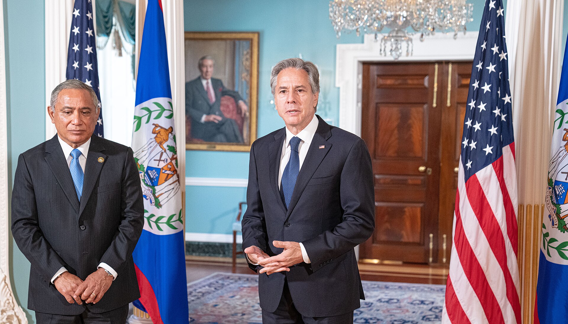 Prime Minister John Briceño, left, stands beside Antony Blinken, who is speaking, with US and Belize flags behind them