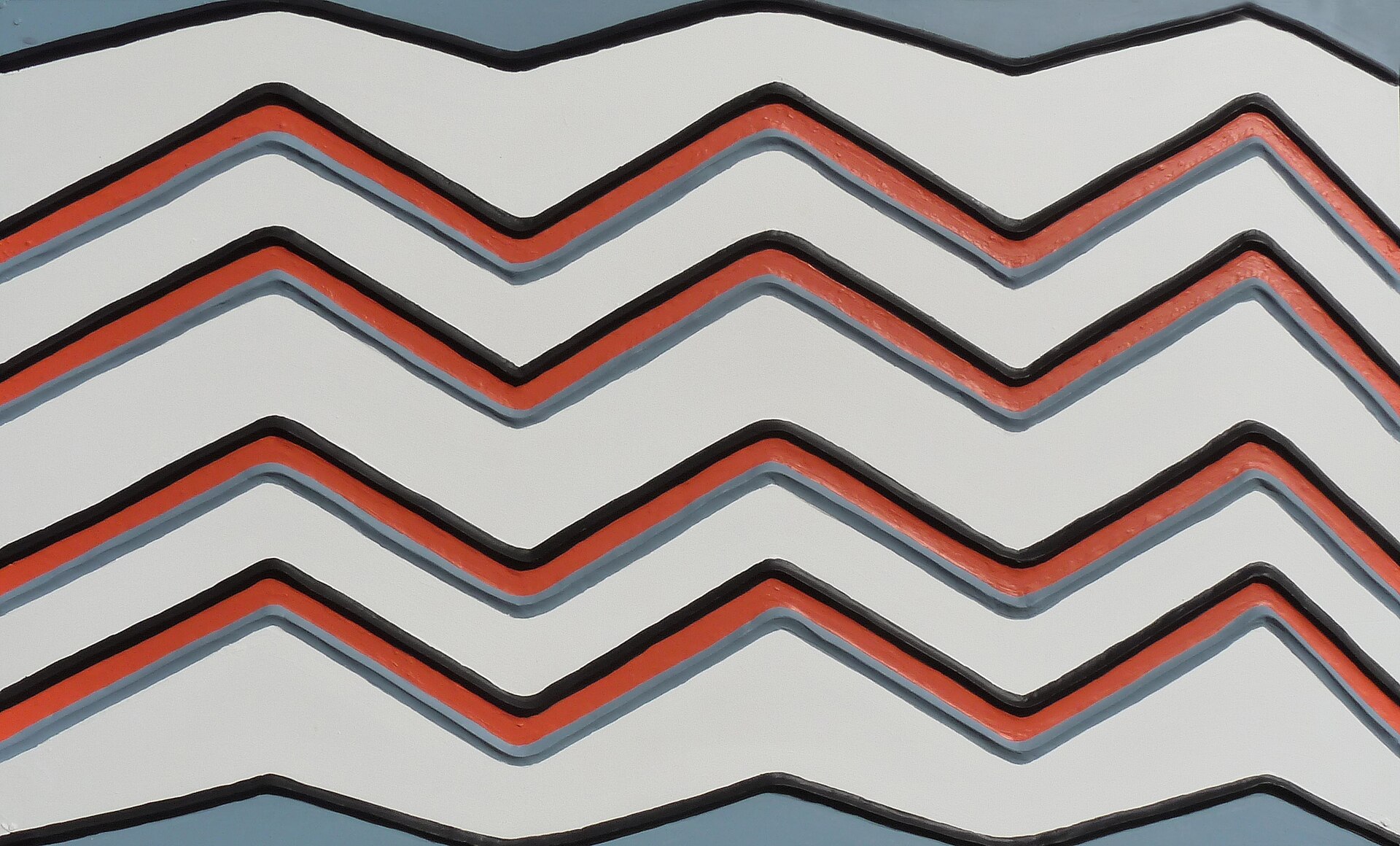Raised zigzag relief pattern in white, red and black on a grey-blue ground, in the Imigongo style