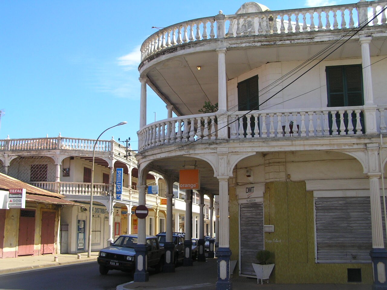 Two storey colonial style buildings with curved white balconies and an arcade on a street corner in Antsiranana, northern Madagascar