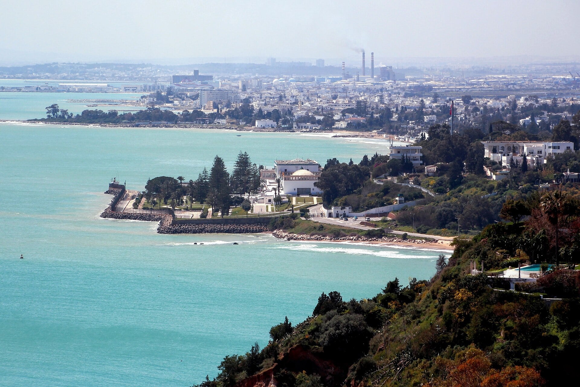 Coastline of the Gulf of Tunis seen from Sidi Bou Said with the white domed Carthage presidential palace among trees on the shore