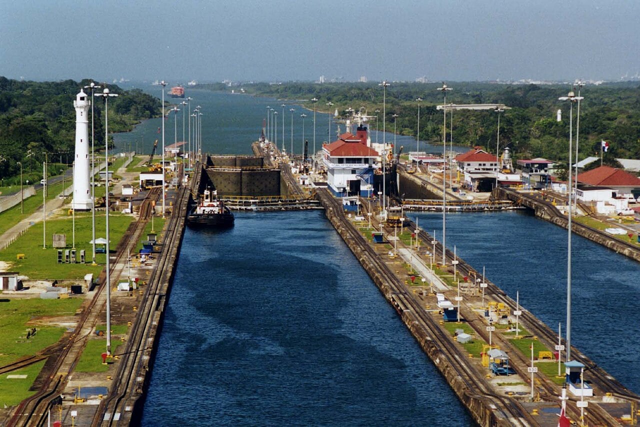 Gatún Locks of the Panama Canal seen from above, with a white lighthouse, a tug and the lock gates on the Atlantic side