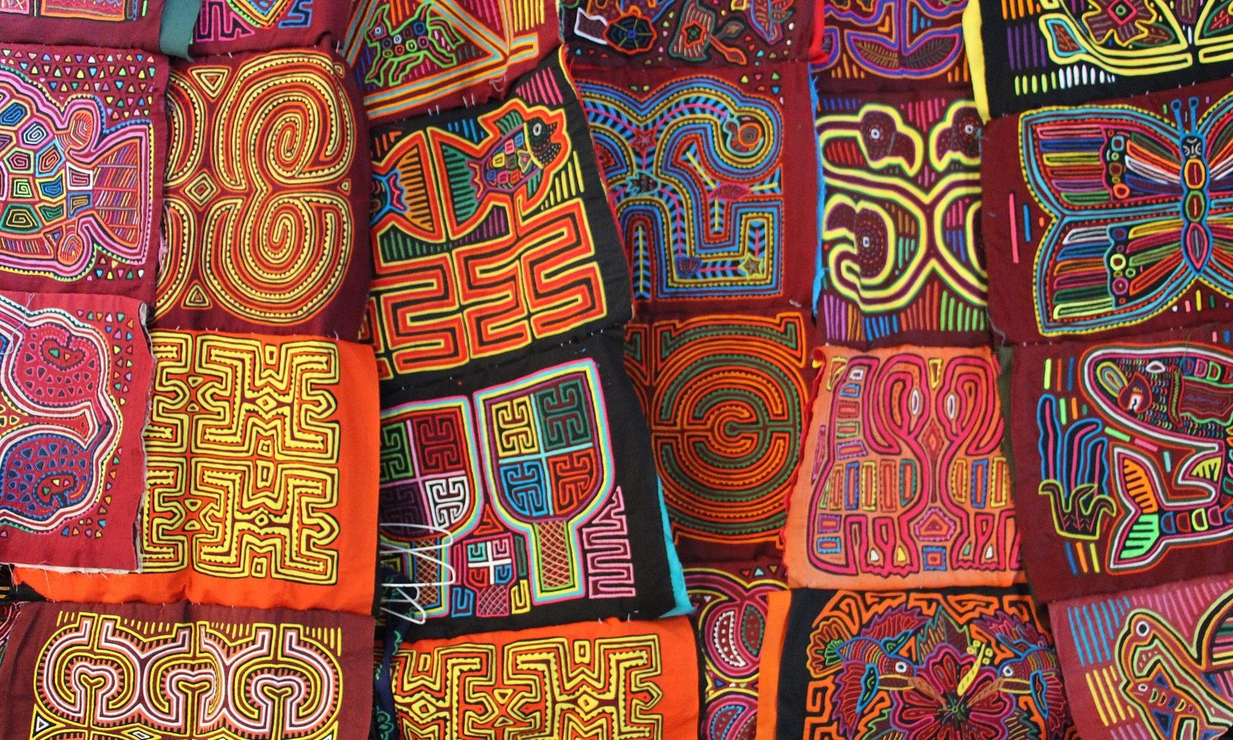 Colourful hand-sewn Guna mola textile panels with geometric and animal patterns laid side by side