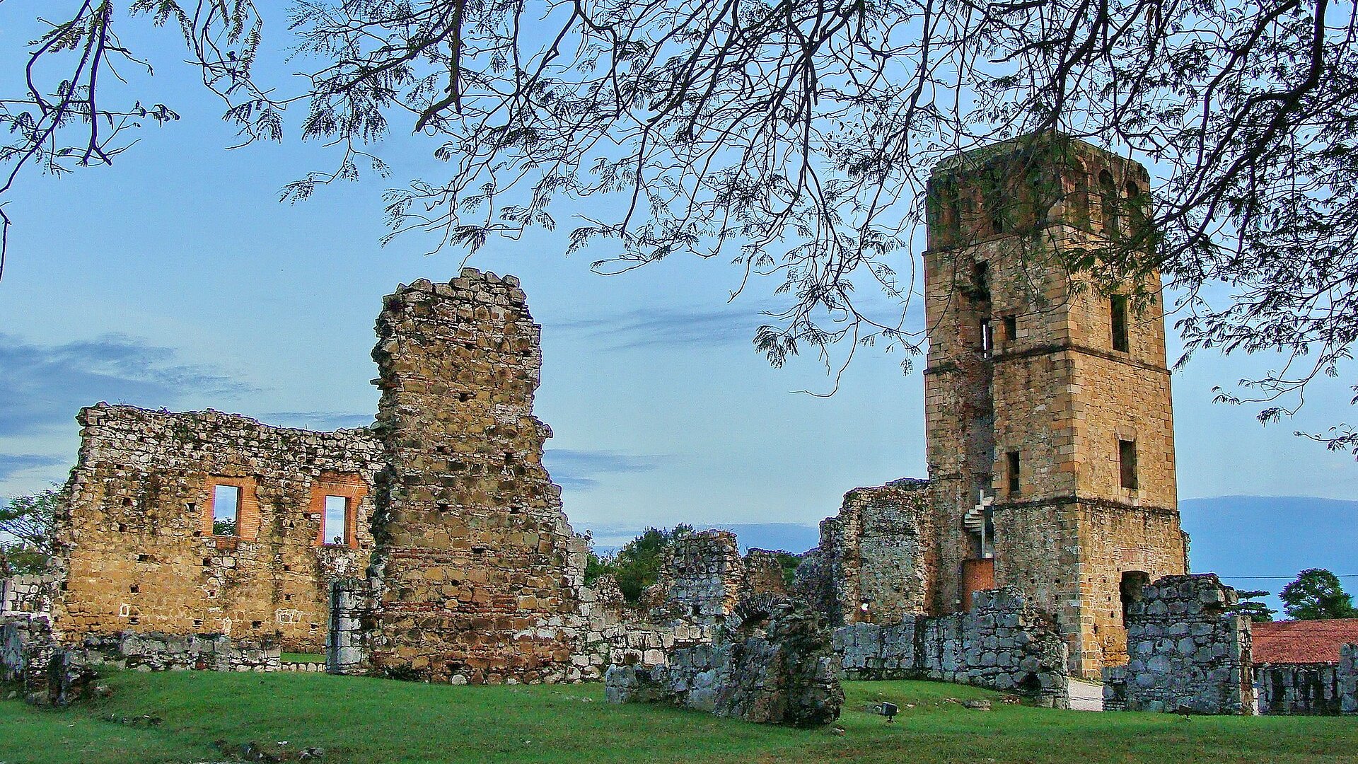 Ruined stone walls and a tall stone tower at the Panamá Viejo archaeological site under a blue sky