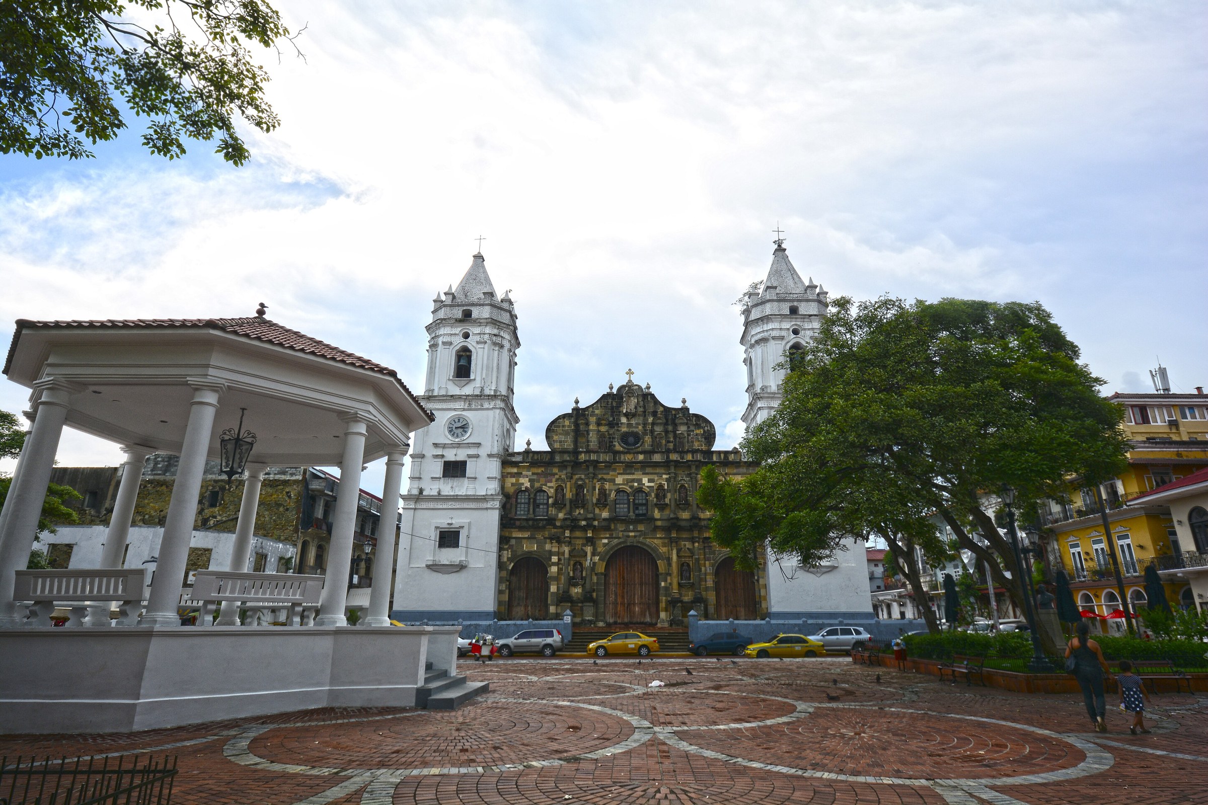 The twin-towered Metropolitan Cathedral behind a white bandstand in a brick-paved plaza in Panama City