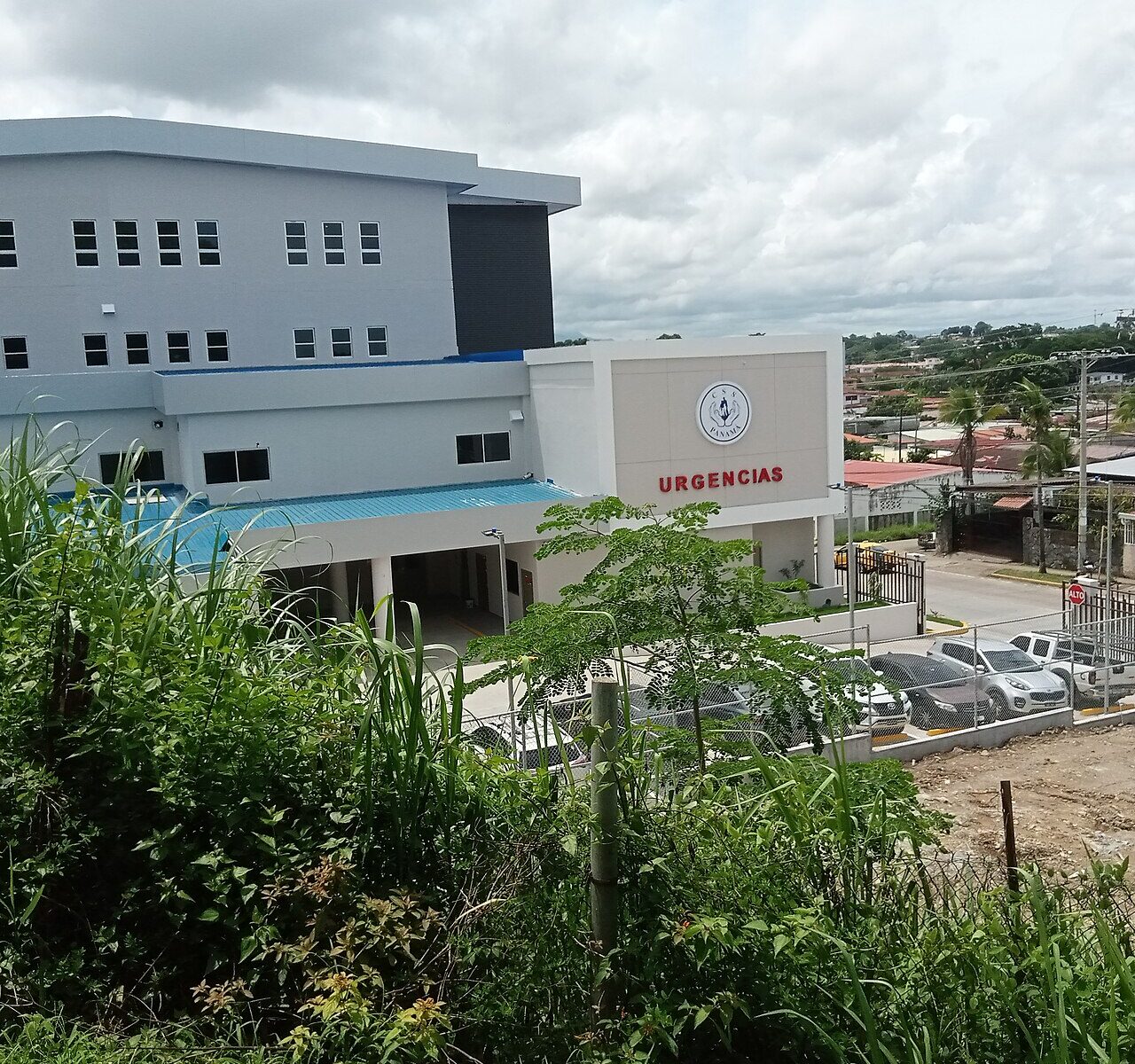A white three-storey Social Security Fund polyclinic with the CSS Panamá logo and an Urgencias emergency sign above a car park in Panama City