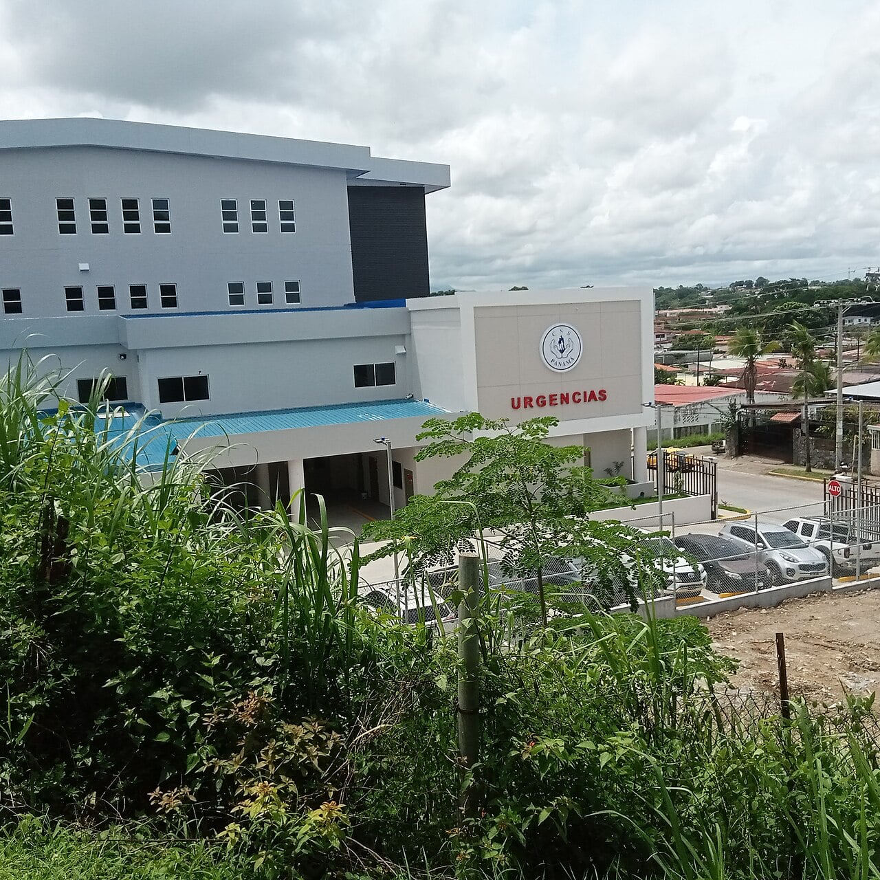 A white three-storey Social Security Fund polyclinic with the CSS Panamá logo and an Urgencias emergency sign above a car park in Panama City