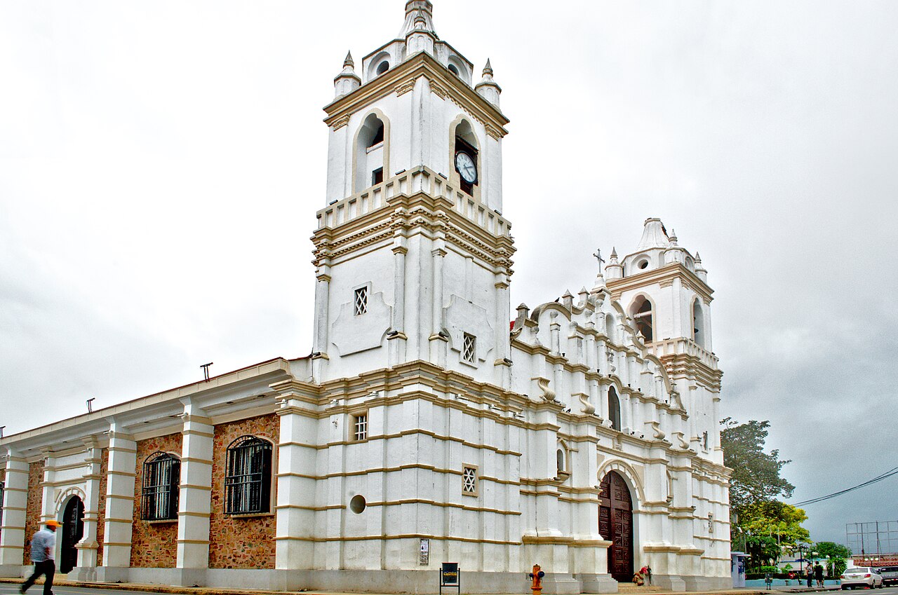 The white twin-towered San Juan Bautista cathedral in Chitré with a clock on one tower, stone walls and a cloudy sky
