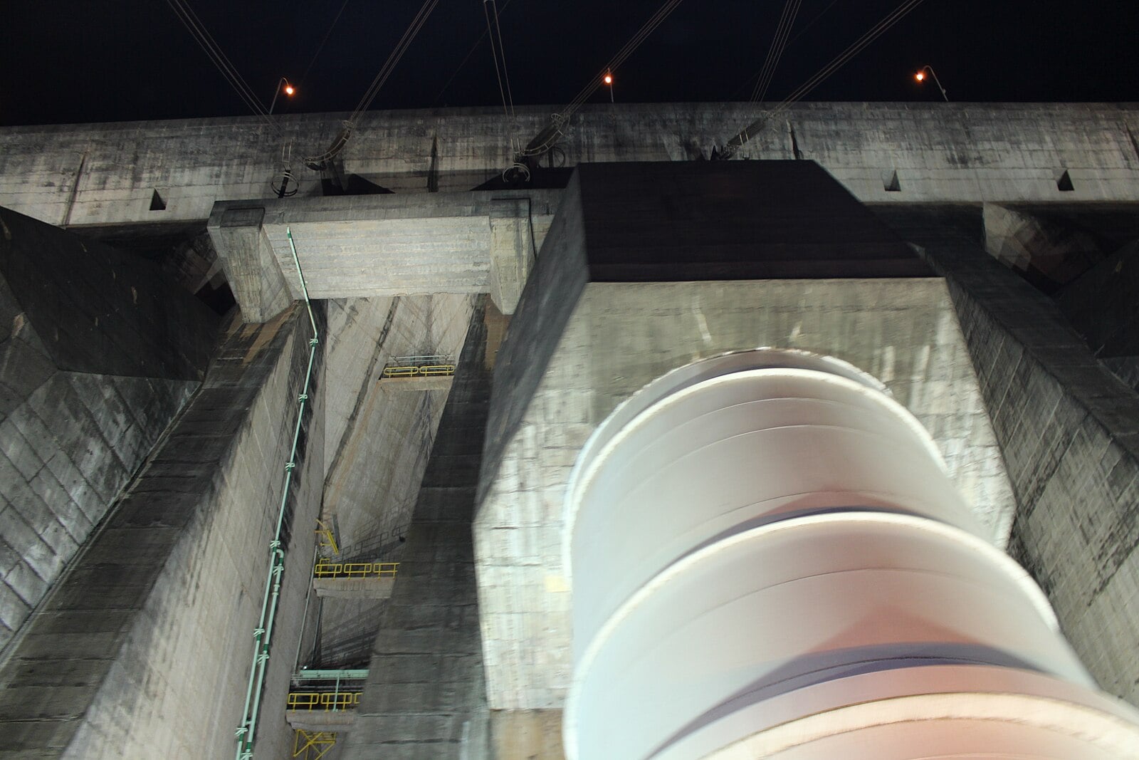 A steel pipe on the concrete face of the Itaipú dam on the Paraná River, photographed at night
