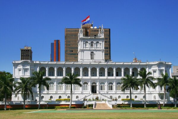 The white Palacio de los López, seat of Paraguay's presidency, with palm trees and the national flag in central Asunción