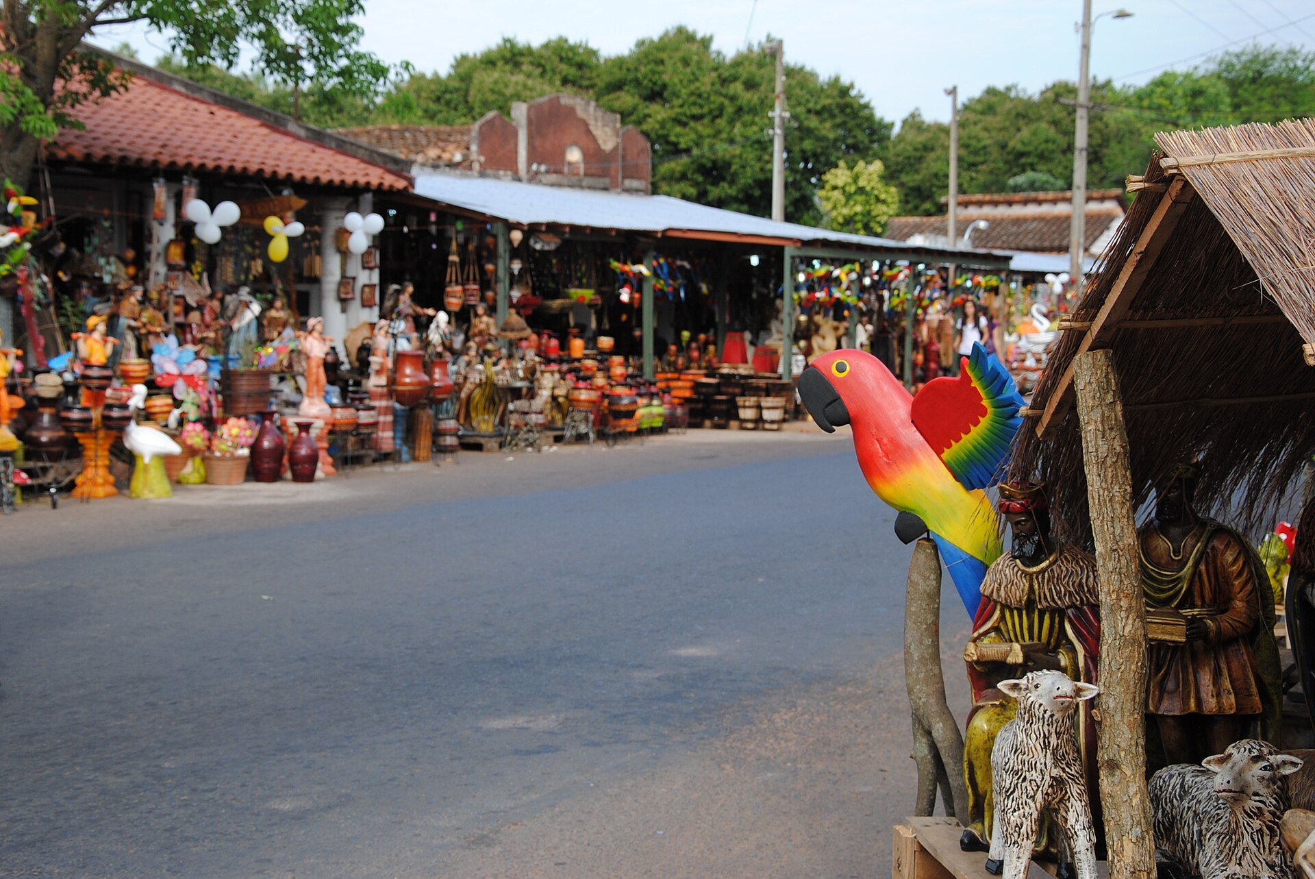 Painted pottery, a carved wooden macaw and nativity figures on sale along a street of craft shops in Areguá, Paraguay
