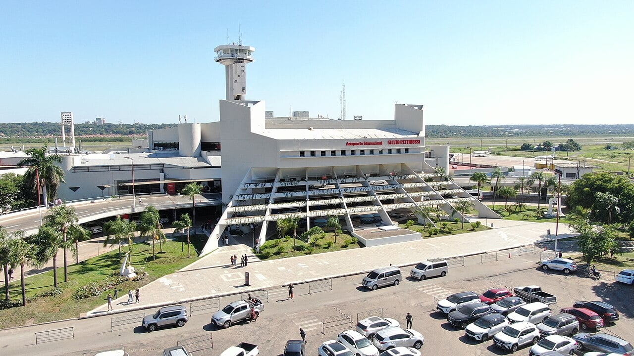 Aerial view of the white terminal and control tower of Silvio Pettirossi International Airport in Luque, Paraguay, with cars parked in front