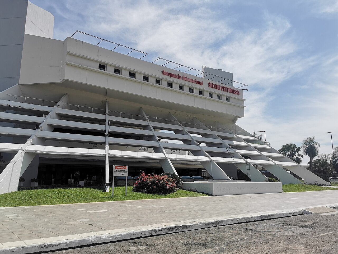 The front of the passenger terminal at Silvio Pettirossi International Airport, with its name in red letters above angled concrete supports
