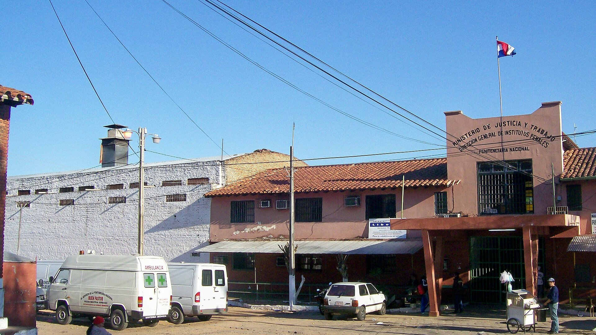 Entrance of the Penitenciaría Nacional prison in Tacumbú, Asunción, with the Paraguayan flag and parked vans