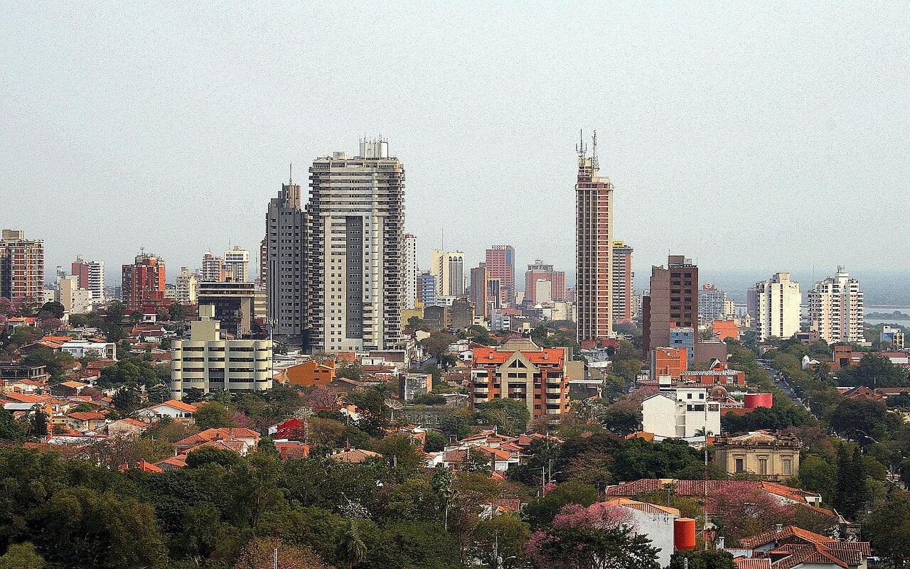 Apartment towers and red-tiled roofs across the centre of Asunción, Paraguay's capital, under a hazy sky