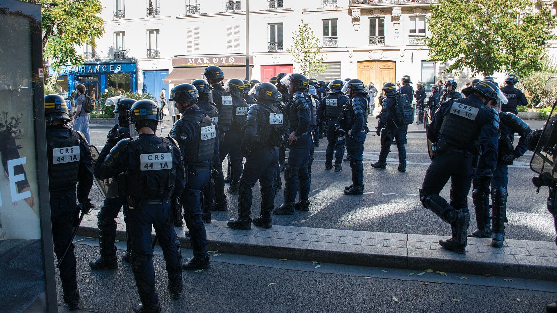 French CRS riot police in helmets and body armour stand in formation on a Paris street near Boulevard Voltaire