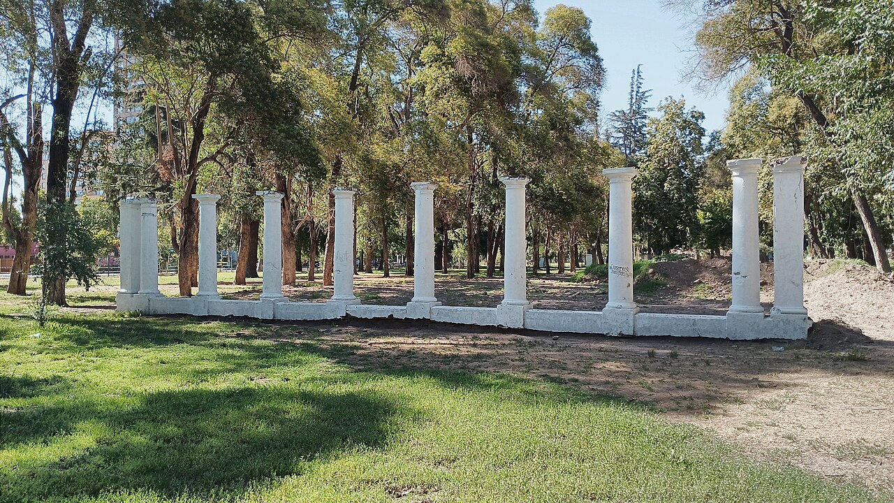 White stone columns standing among tall trees on the grass of Parque O'Higgins in Santiago.