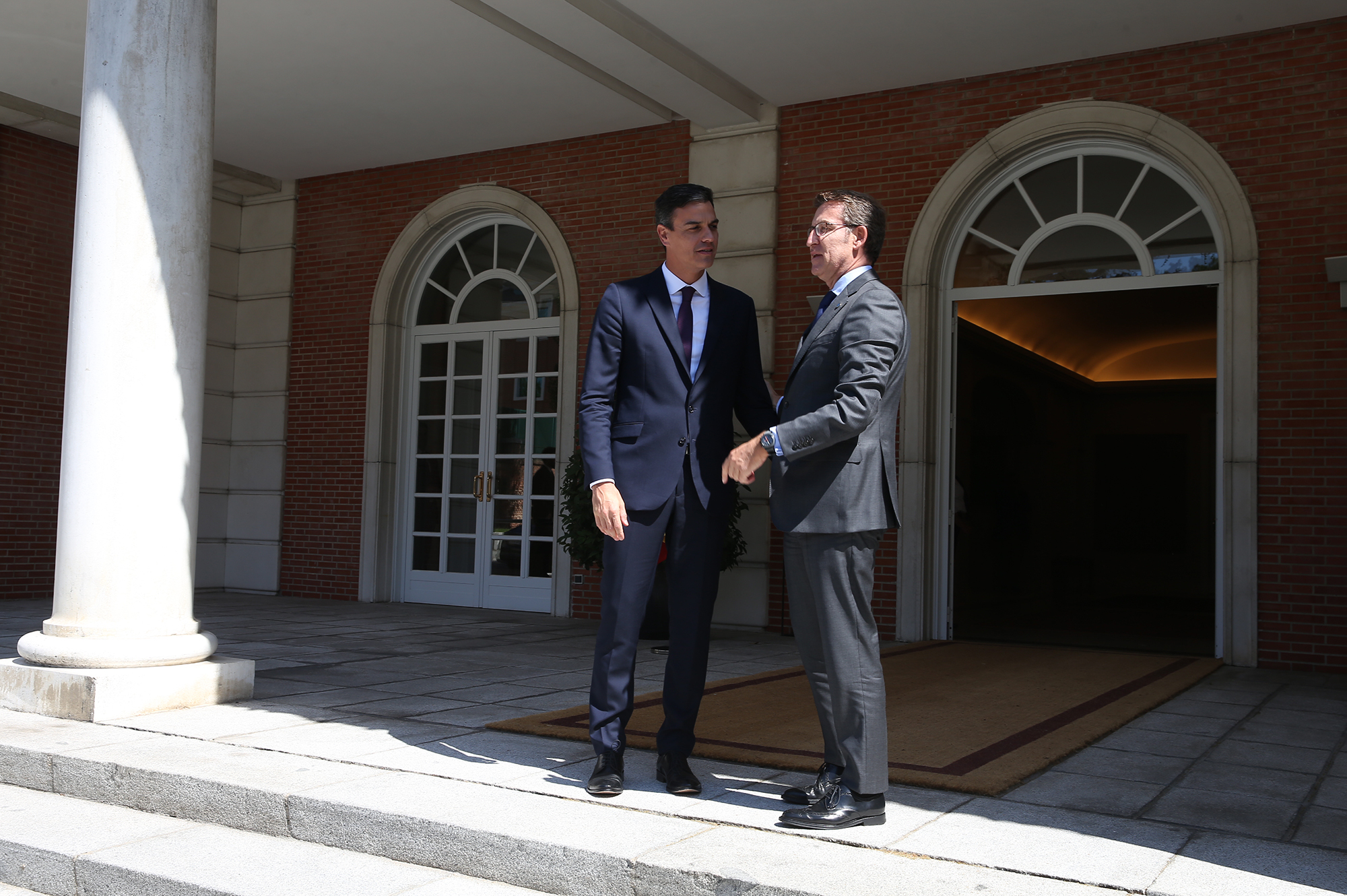 Pedro Sánchez shakes hands with Alberto Núñez Feijóo outside the Moncloa Palace in Madrid
