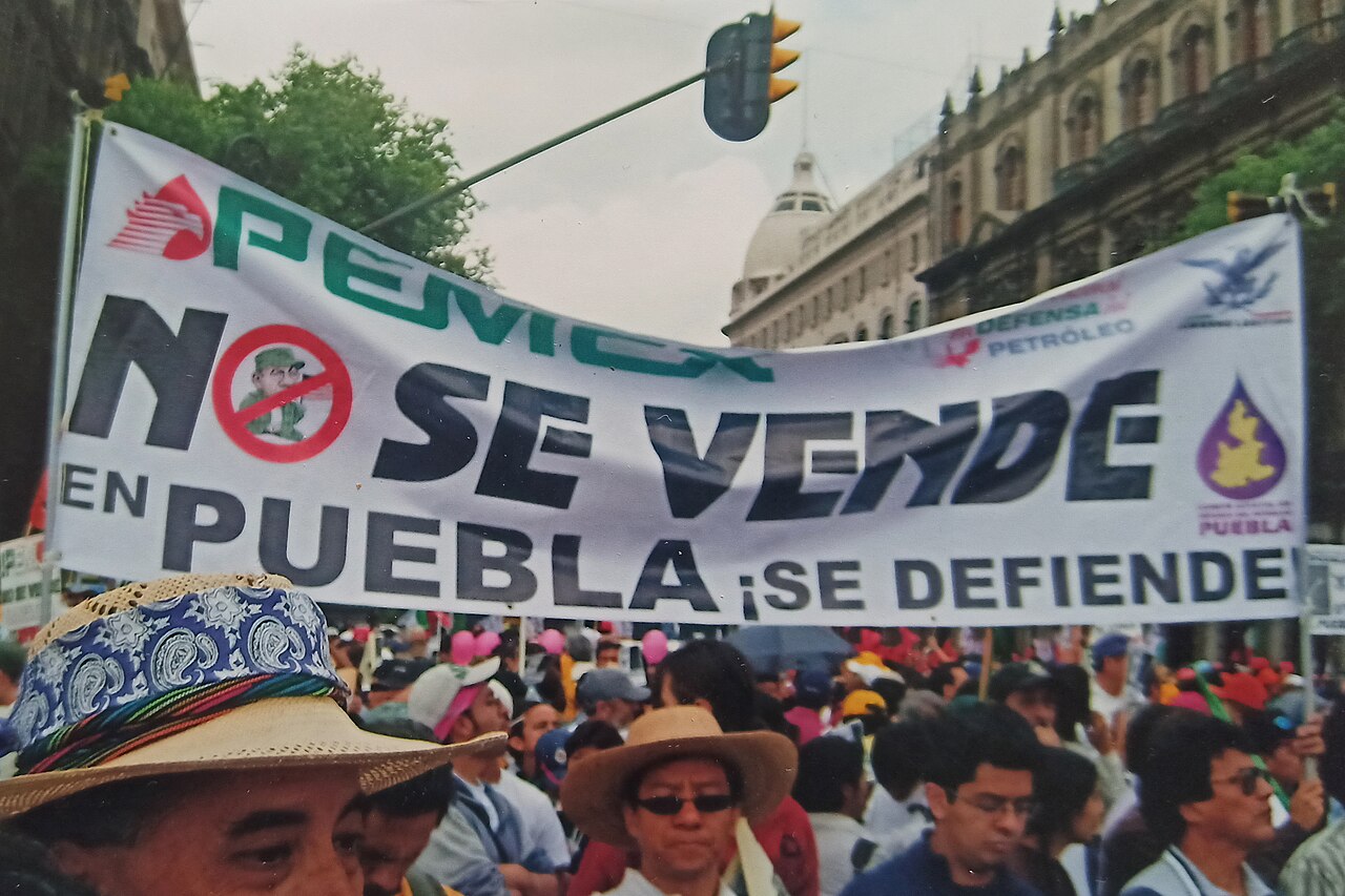 Protesters in Mexico City march behind a large banner reading Pemex no se vende en Puebla, se defiende, Pemex is not for sale